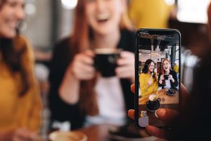 person taking a picture of two women at a coffee shop