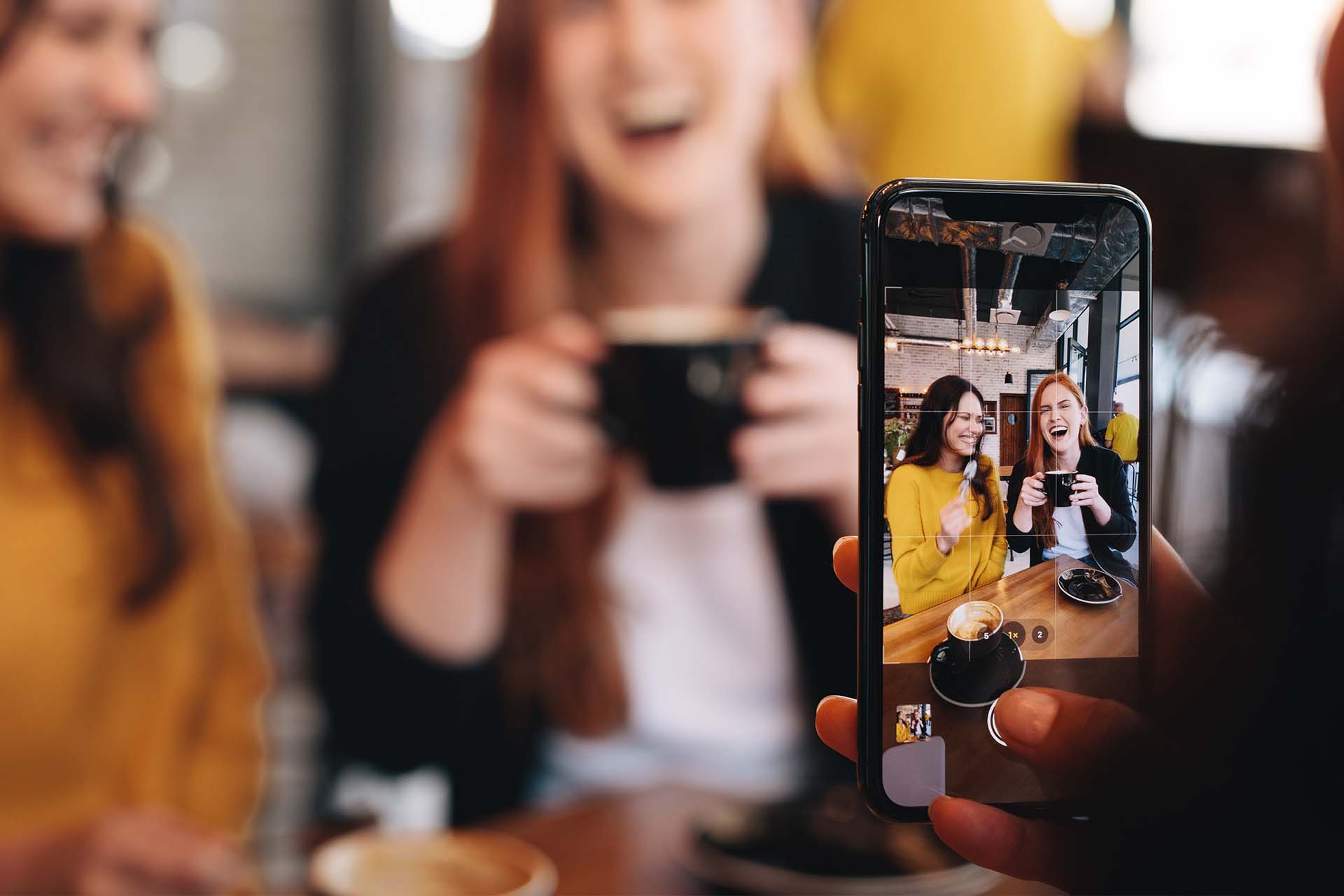 person taking a picture of two women at a coffee shop