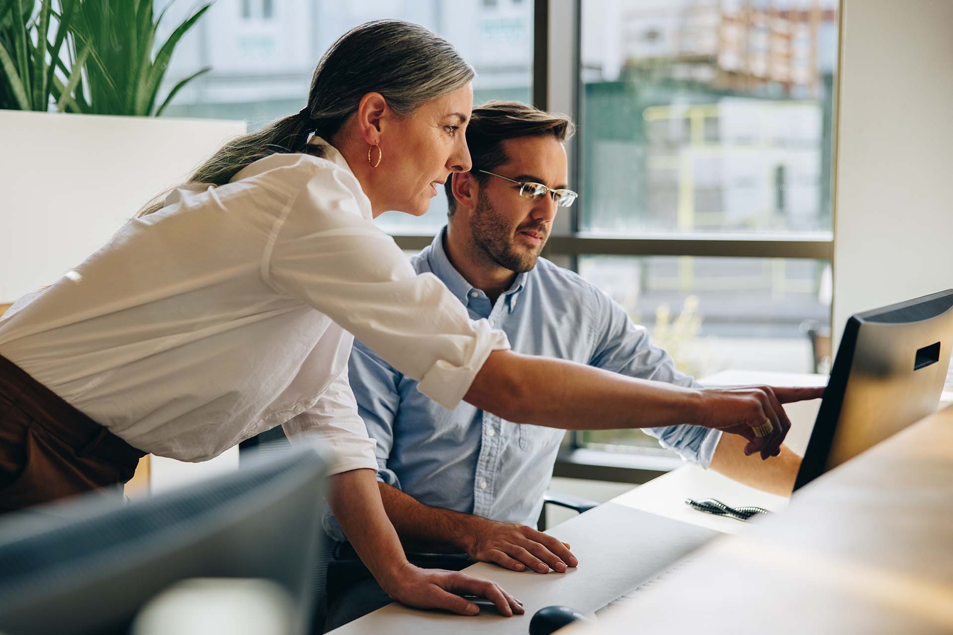 woman and man looking at a computer, woman is pointing to something on the screen
