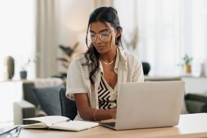 woman looking at notes while typing on a computer