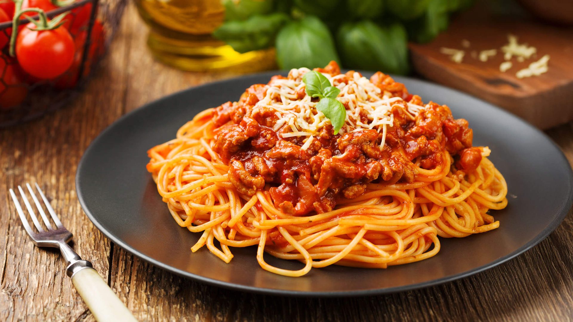 a plate of spaghetti while different ingredients are in the background