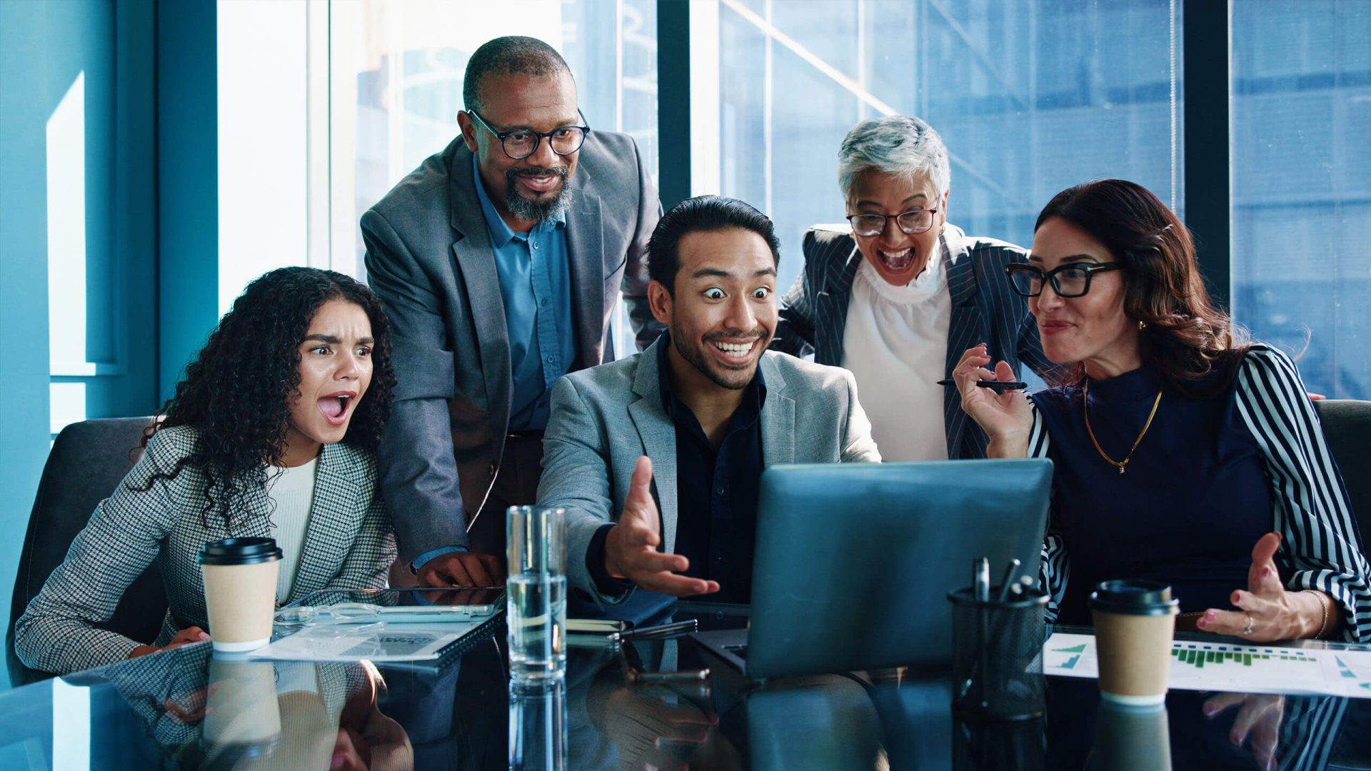a group of business people looking in pleasant surprise at a computer screen
